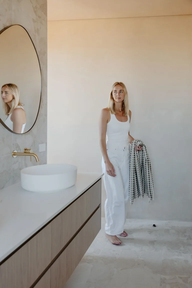 Ensuite with a floating oak-look vanity, round vessel basin and pebble mirror, finished with soft rendered walls and large-format stone-look floor tiles
