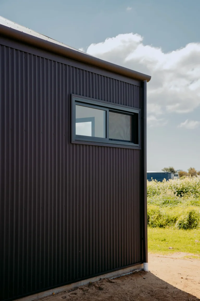 Dark corrugated metal cladding and black-framed window on the exterior of the Felling Karridale home