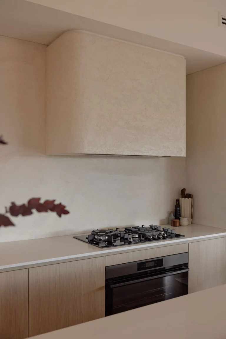 Close-up of the hand-textured rendered rangehood and seamless render splashback above the gas cooktop