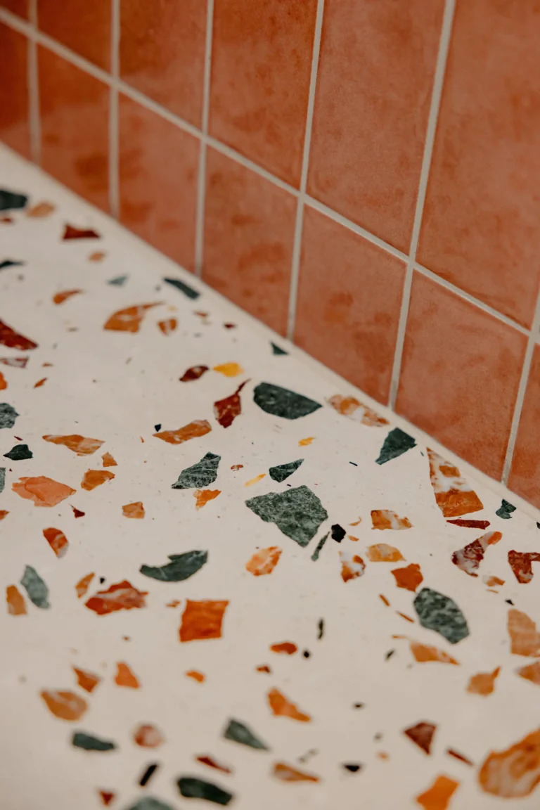 Terrazzo shower step detail against a terracotta tiled wall