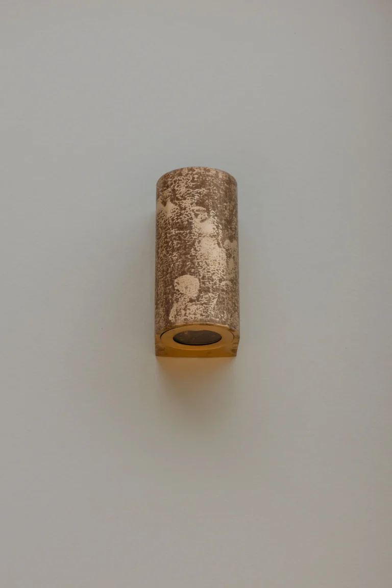 Cylindrical up-and-down exterior wall light mounted on a pale rendered wall