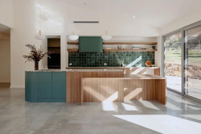 Sunlit open-plan kitchen with sage-green fluted cabinetry, a terrazzo island bench and pendant lighting