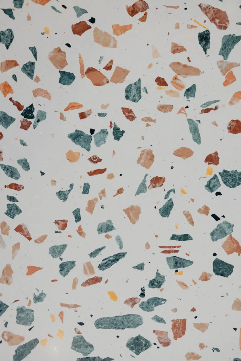 Close-up of a terrazzo benchtop with green, terracotta and charcoal aggregate on a pale base
