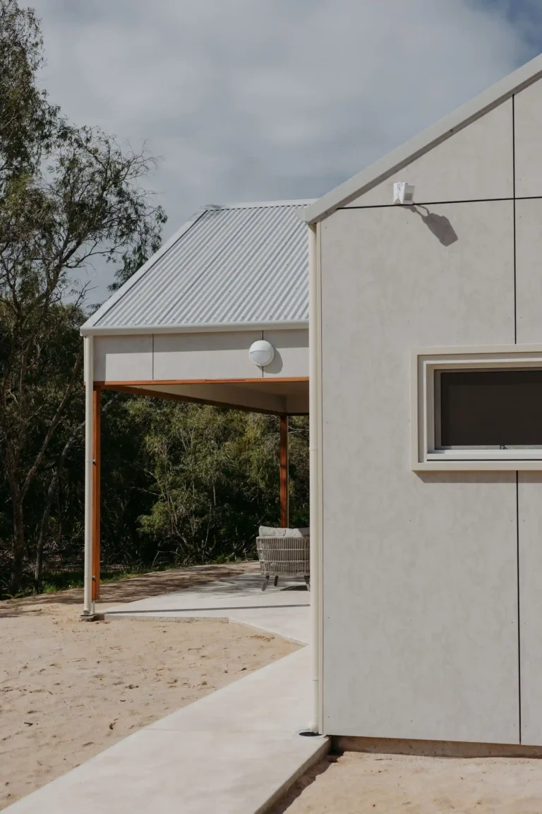 Covered alfresco with timber beams beside the cabin's panelled gable wall