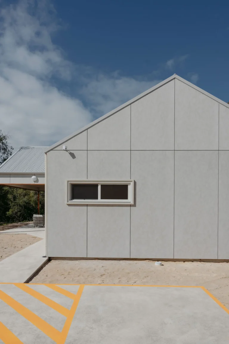 Gable end of the barn-style cabin with slim window and accessible parking bay