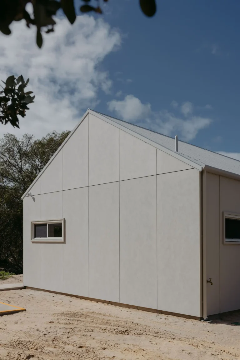 Side view of the barn-style cabin with pale panelled cladding and a small window
